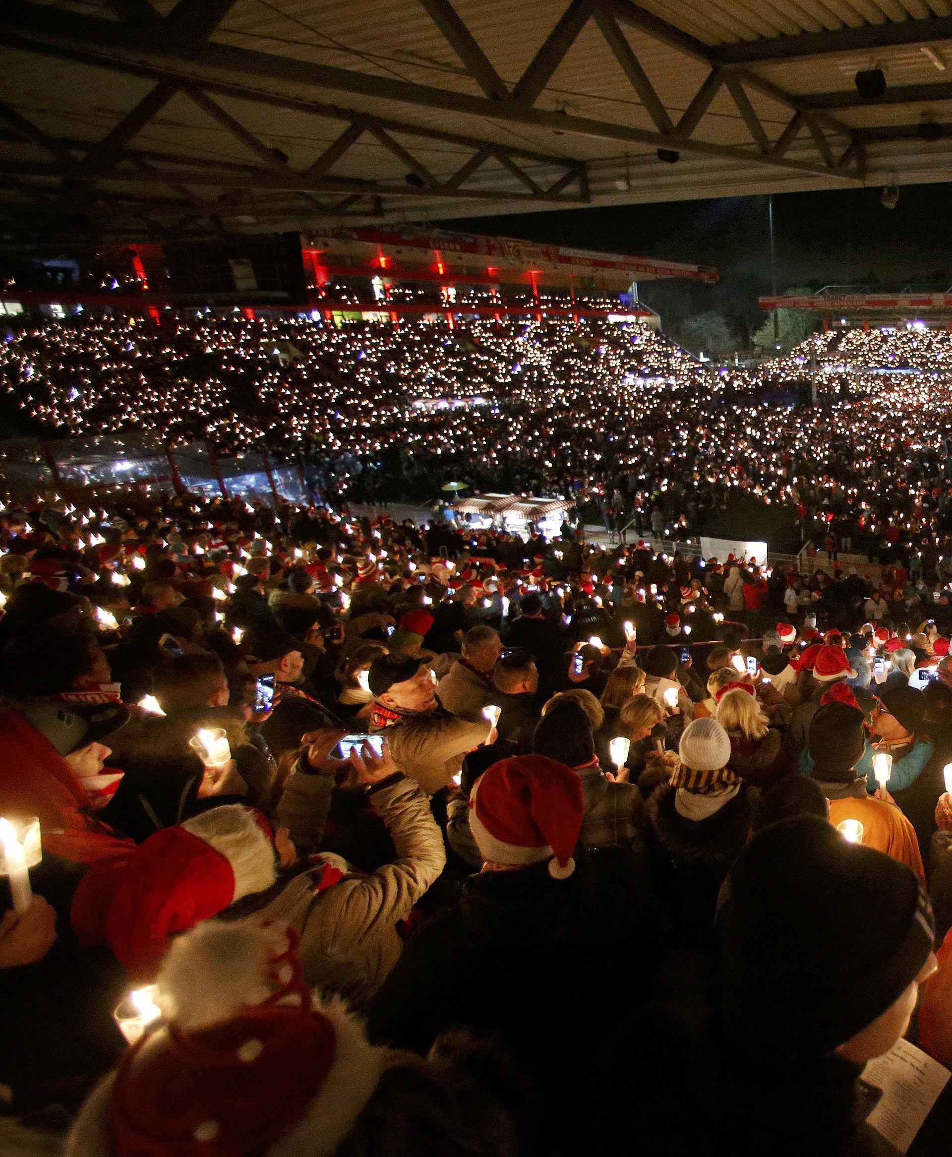 People attend the "Weihnachtssingen", a candle-lit carol concert at the Alte Foersterei stadium in Berlin