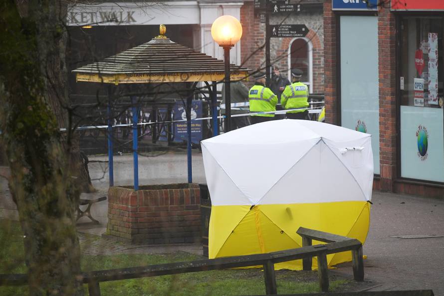 Police officers stand at crime scene tape, as a tent covers a park bench on which former Russian inteligence officer Sergei Skripal, and a woman were found unconscious after they had been exposed to an unknown substance, in Salisbury