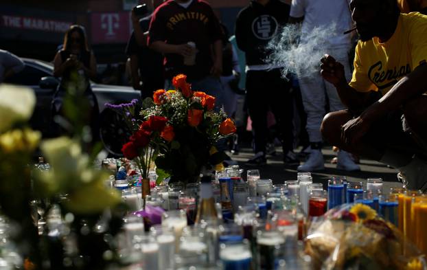 A person smokes by a makeshift memorial for Grammy-nominated rapper Nipsey Hussle who was shot and killed outside his clothing store in Los Angeles