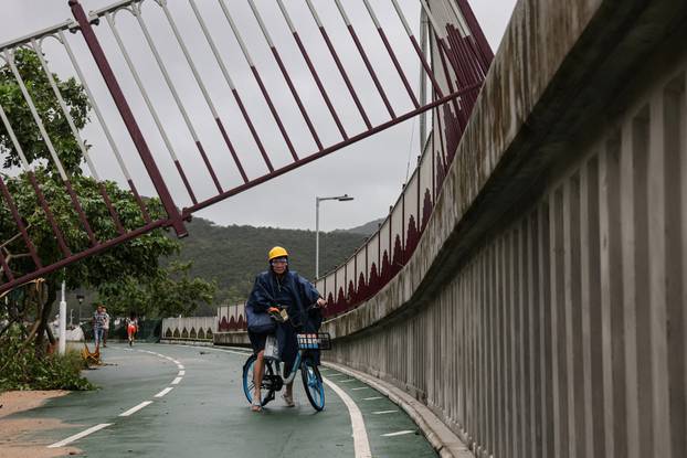 A cyclist looks at a broken fence on a cycle path damaged by Super Typhoon Ragasa in Hong Kong