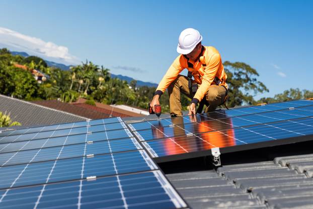 Solar,Panel,Technician,With,Drill,Installing,Solar,Panels,On,House