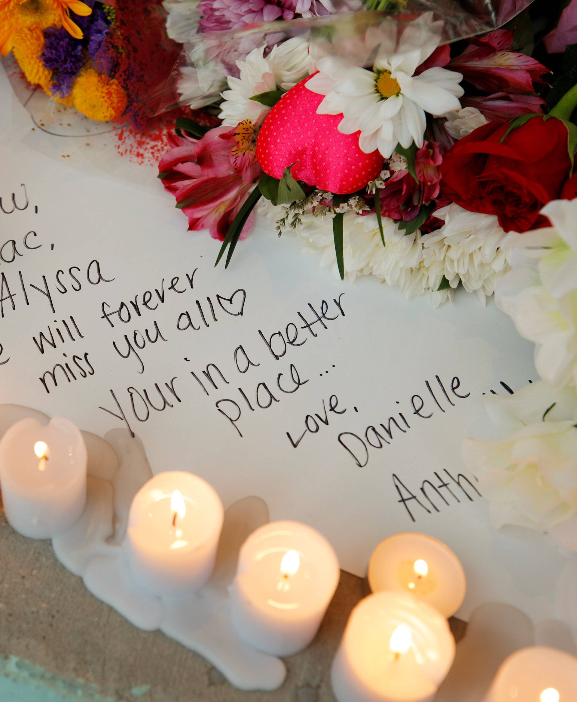 A handwritten note to a lost friend is surrounded by candles and flowers at a candlelight vigil the day after a shooting at Marjory Stoneman Douglas High School in Parkland