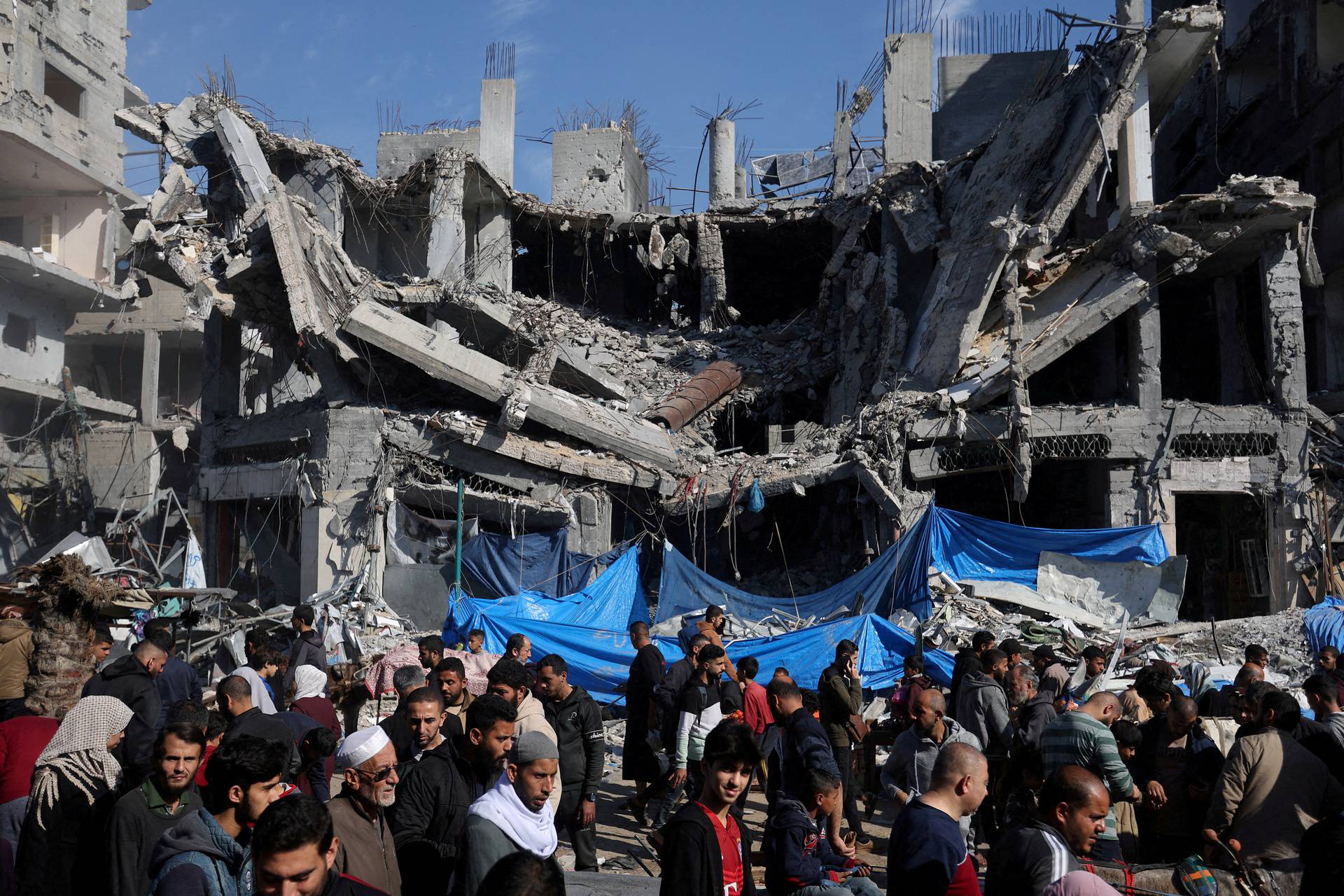 FILE PHOTO: Palestinians shop near the ruins of houses and buildings destroyed in Israeli strikes during the conflict