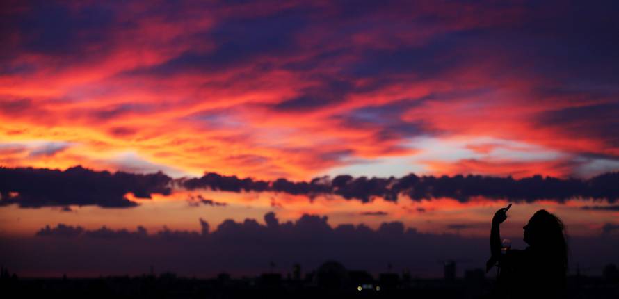 A woman takes pictures of a sunset close to the square Potsdamer Platz in Berlin