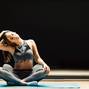 Sporty woman in stretching sitting in lotus position on rug in sports hall