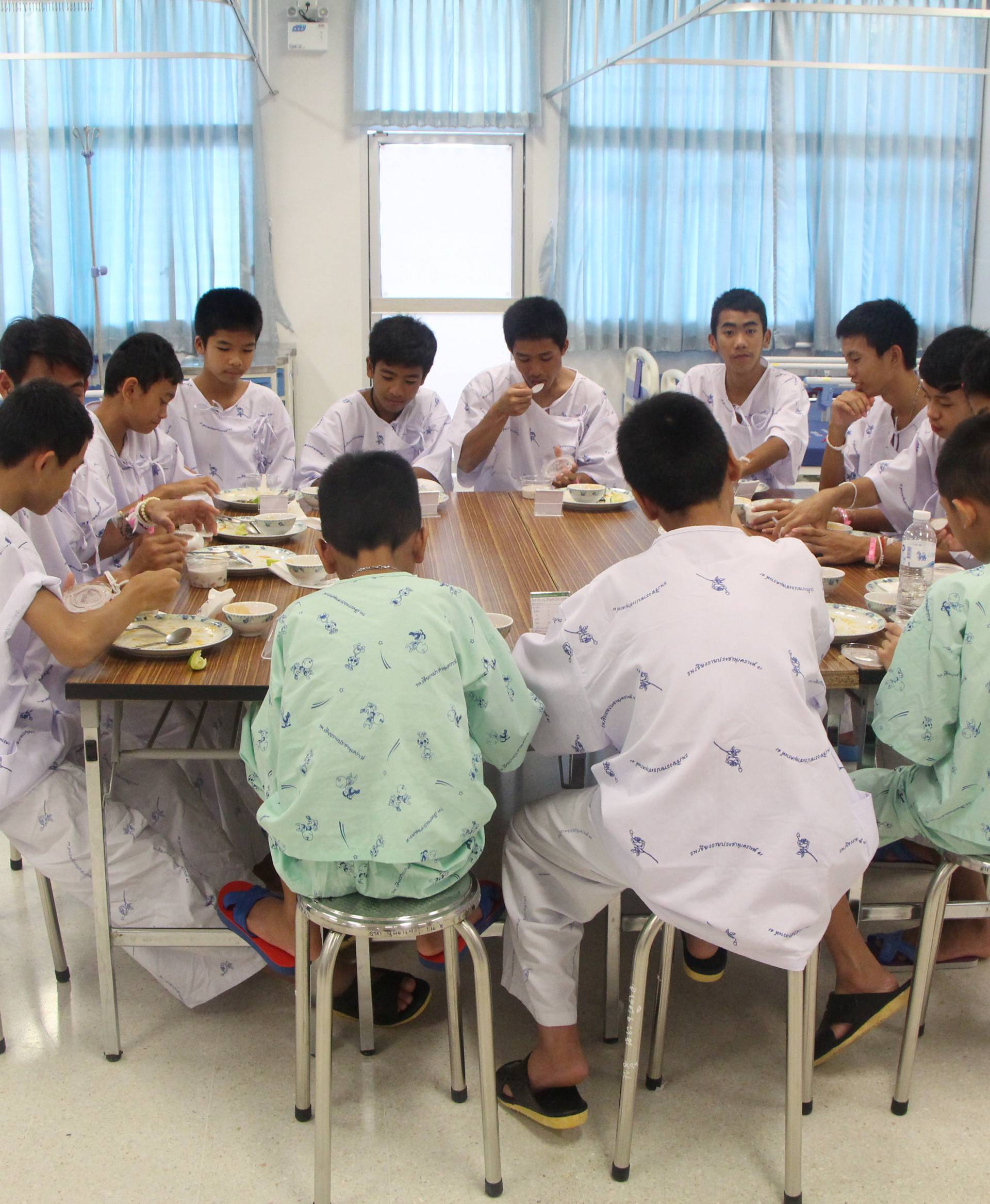 Twelve members of "Wild Boars" soccer team and their coach rescued from a flooded cave eat at the Chiang Rai Prachanukroh Hospital, in Chiang Rai