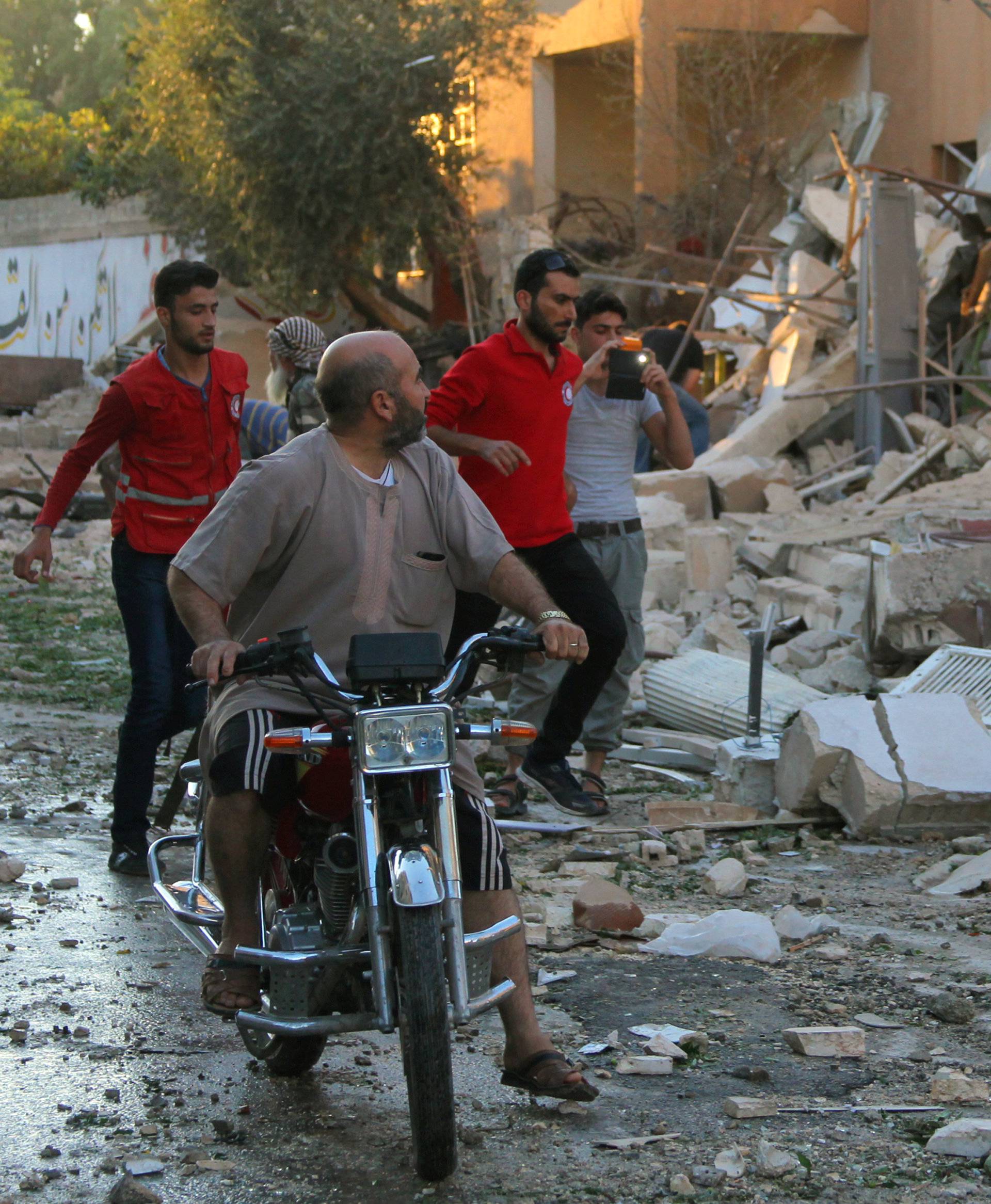 Syrian Arab Red Crescent members rush to a site hit by airstrikes in Idlib