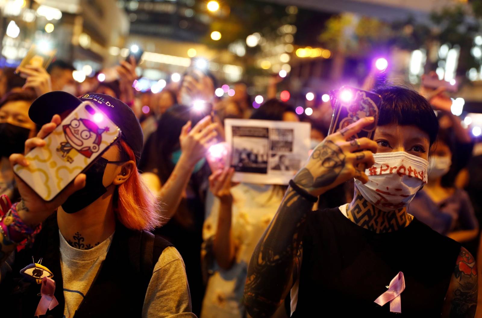 Protesters hold up their phones as they gather to condemn alleged sexual harassment of a detained demonstrator at a police station, in Hong Kong