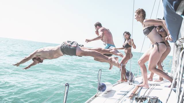 Friends jumping in the water from the boat