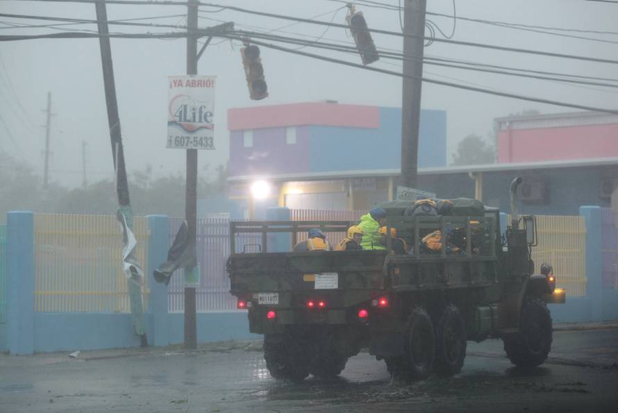 Members of the civil defense ride on a truck as Hurricane Irma howls past Puerto Rico after thrashing several smaller Caribbean islands, in Fajardo