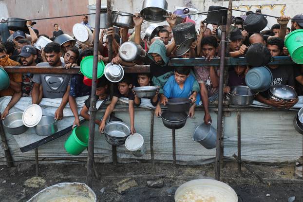 Palestinians wait to receive food from a charity kitchen, amid a hunger crisis, in Gaza City
