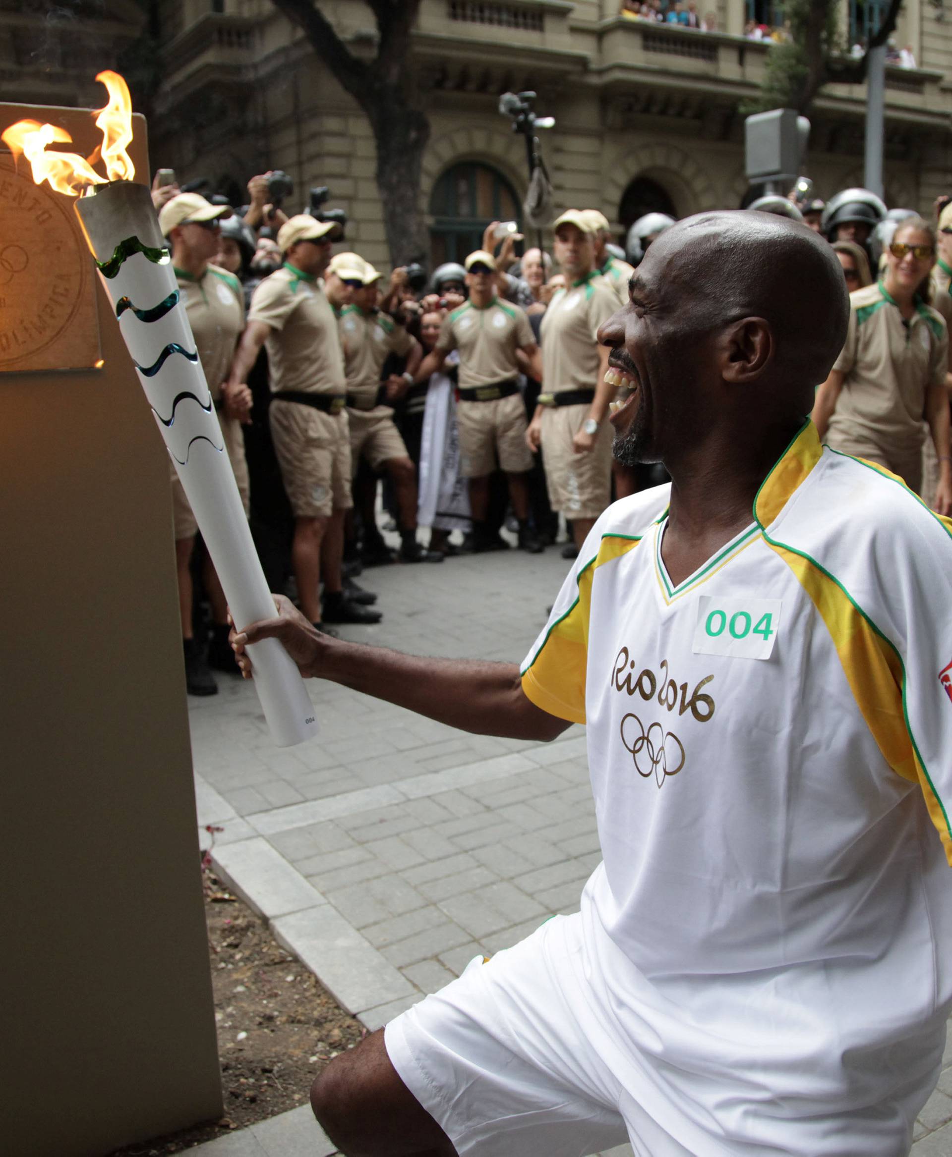 Street sweeper Renato Sorriso smiles while lighting the first of five posts with the Olympic torch in Rio de Janeiro