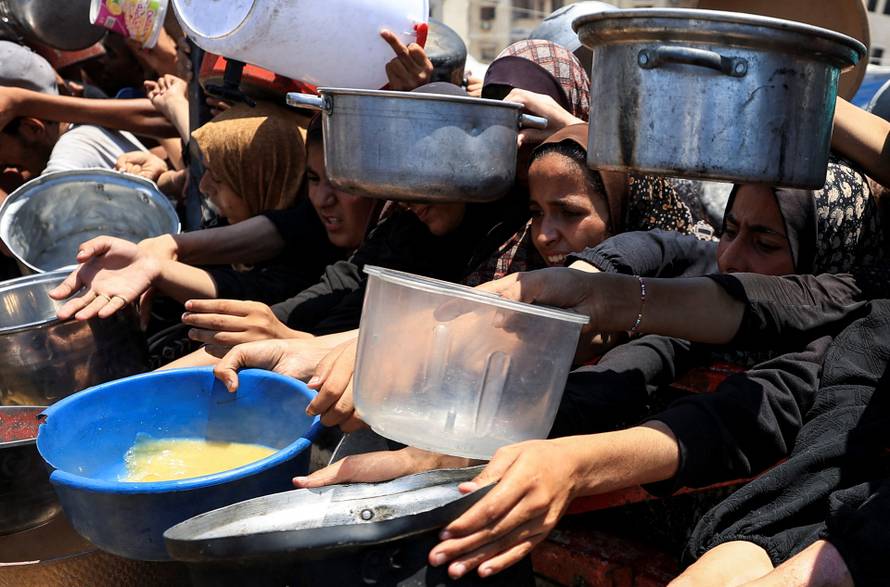 Palestinians wait to receive food from a charity kitchen, in Gaza City