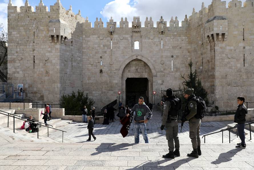 A Palestinian man removes his jacket during a security check by Israeli border policemen at Damascus Gate in Jerusalem's Old City