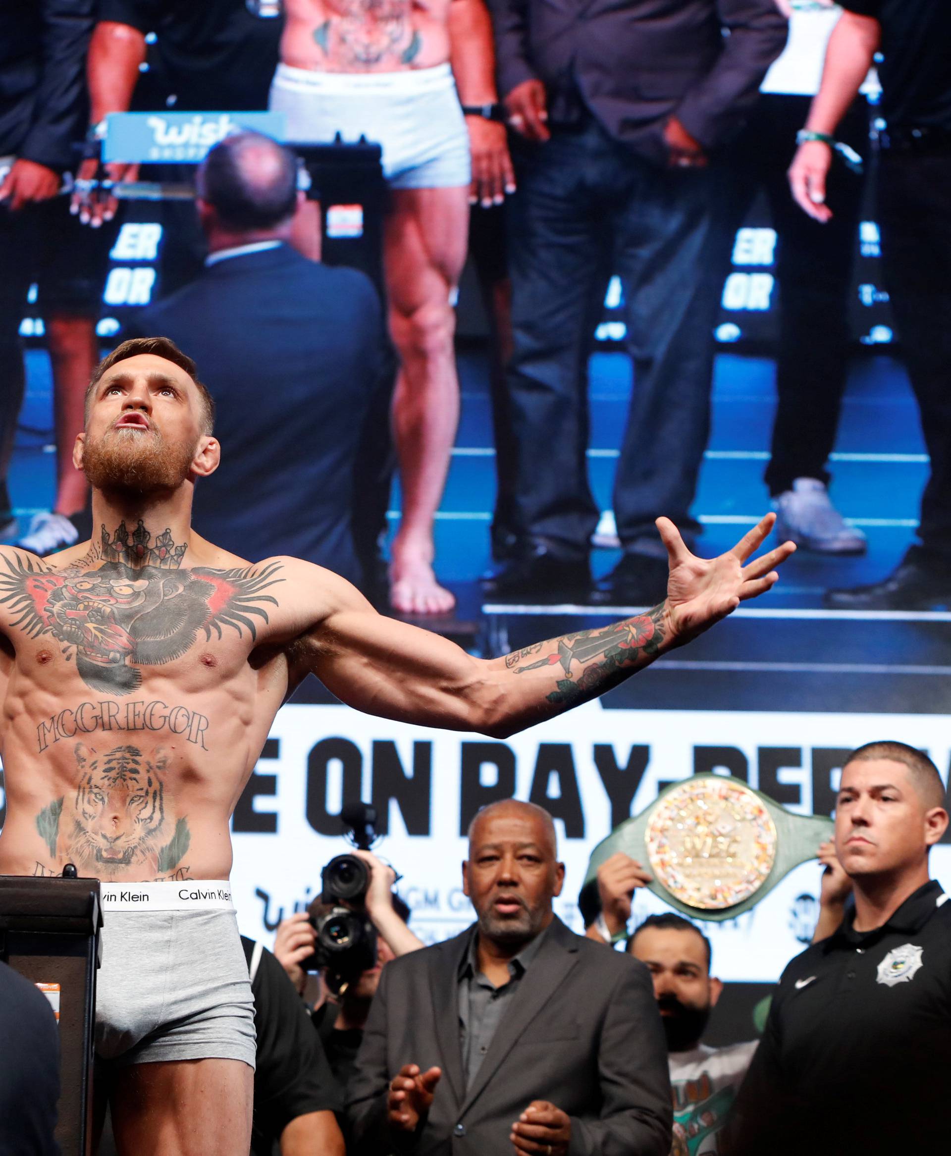 UFC lightweight champion Conor McGregor of Ireland poses on the scale during his official weigh-in at T-Mobile Arena in Las Vegas
