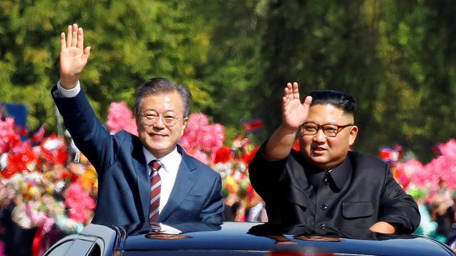 South Korean President Moon Jae-in and North Korean leader Kim Jong Un wave during a car parade in Pyongyang