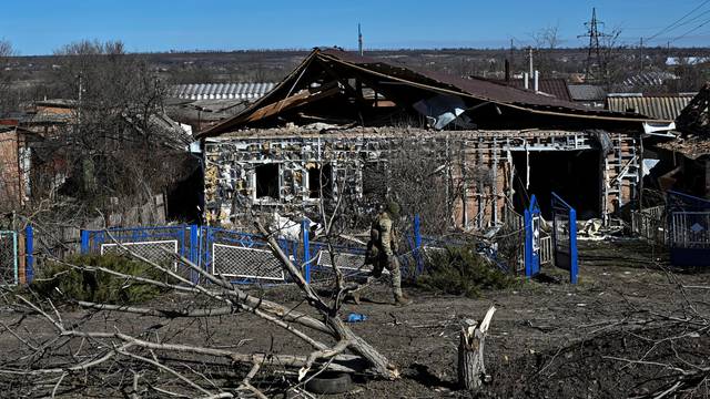 Police officer walks past a damaged house in the frontline town of Orikhiv