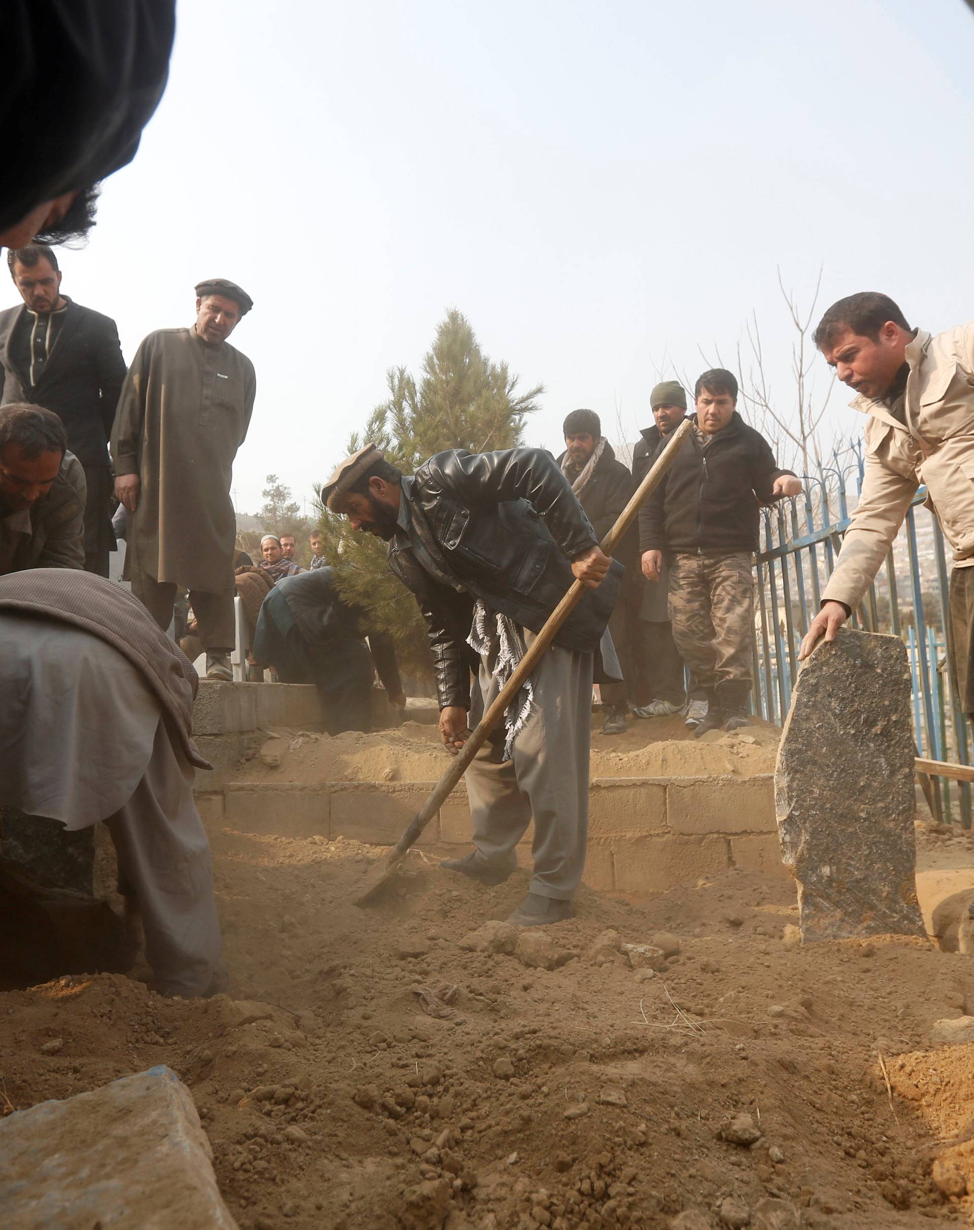 Afghan men attend a burial ceremony of one of the victims of yesterday's car bomb attack in Kabul, Afghanistan