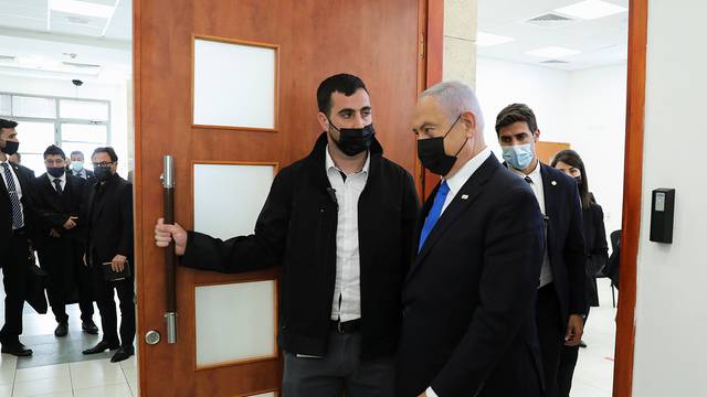 Israeli Prime Minister Benjamin Netanyahu, wearing a face mask, leaves the courtroom during a hearing as his corruption trial resumes, at Jerusalem's District Court