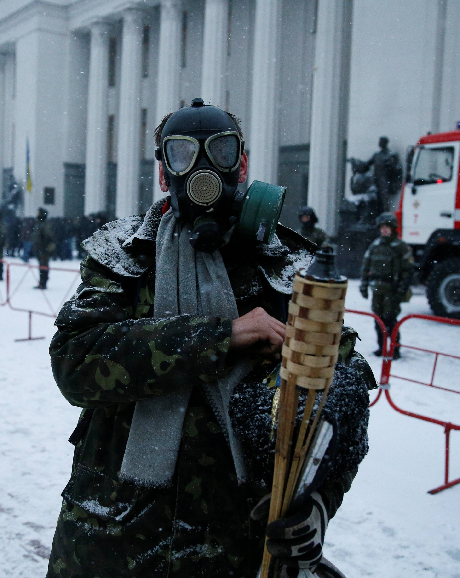 An anti-government protester wearing a gasmask stands in front of the Parliament building in Kiev