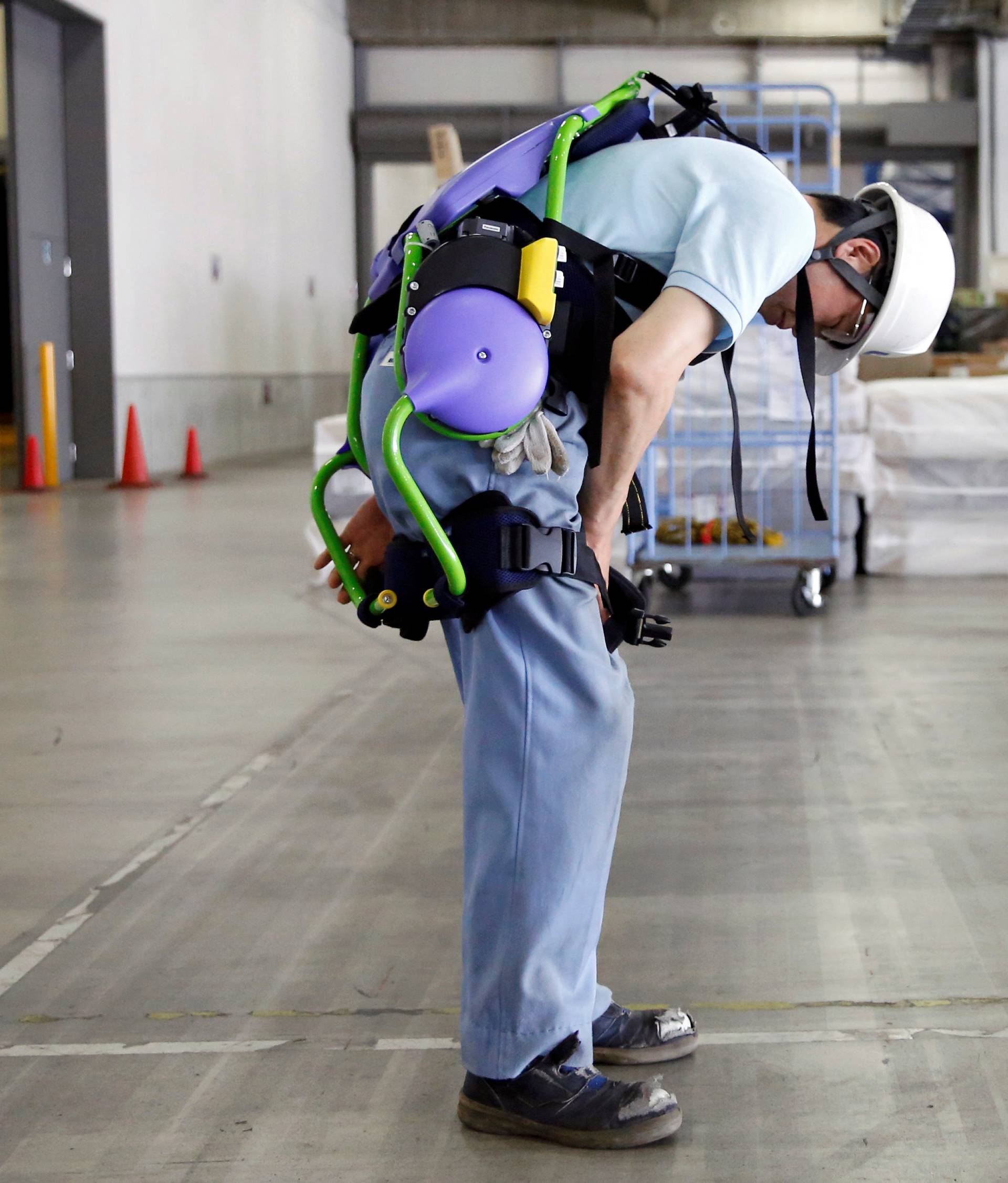 Okutani, 57, a contract worker of Ueda Co., Ltd., wears an Atoun Inc. Power Assist Suit at a distribution center in Kawasaki