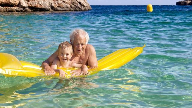 Senior Man And Grandson having fun On Inflatable Air Bed