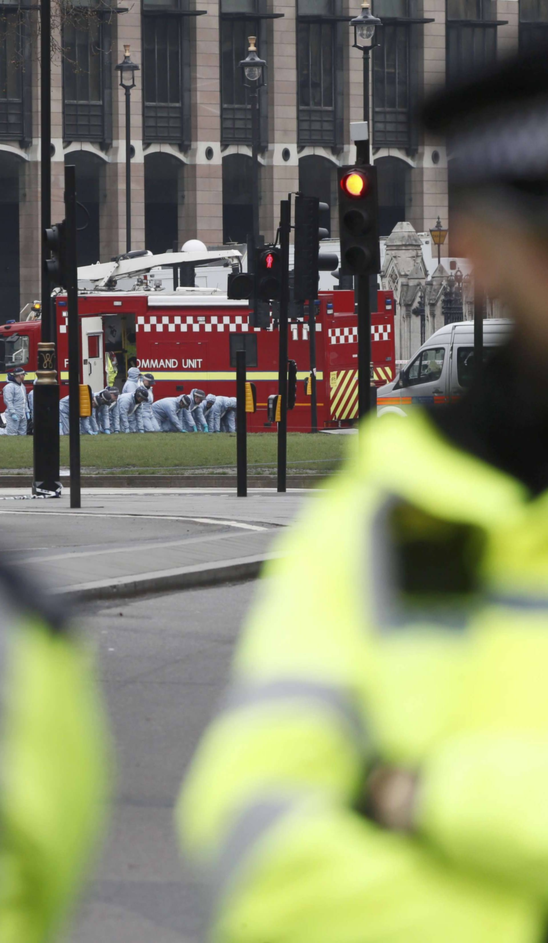 Forensic officers search on their hands and knees next to the Houses of Parliament the day after an attack, in London