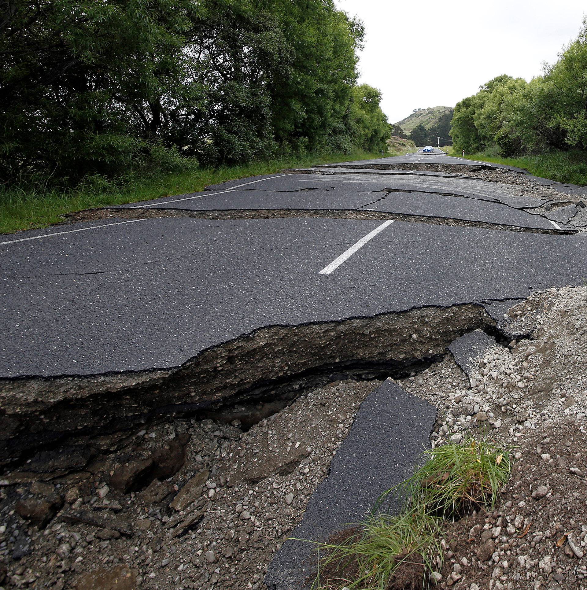 A four-wheel-drive vehicle negotiates the damaged State Highway One near the town of Ward, south of Blenheim, following an earthquake on New Zealand's South Island