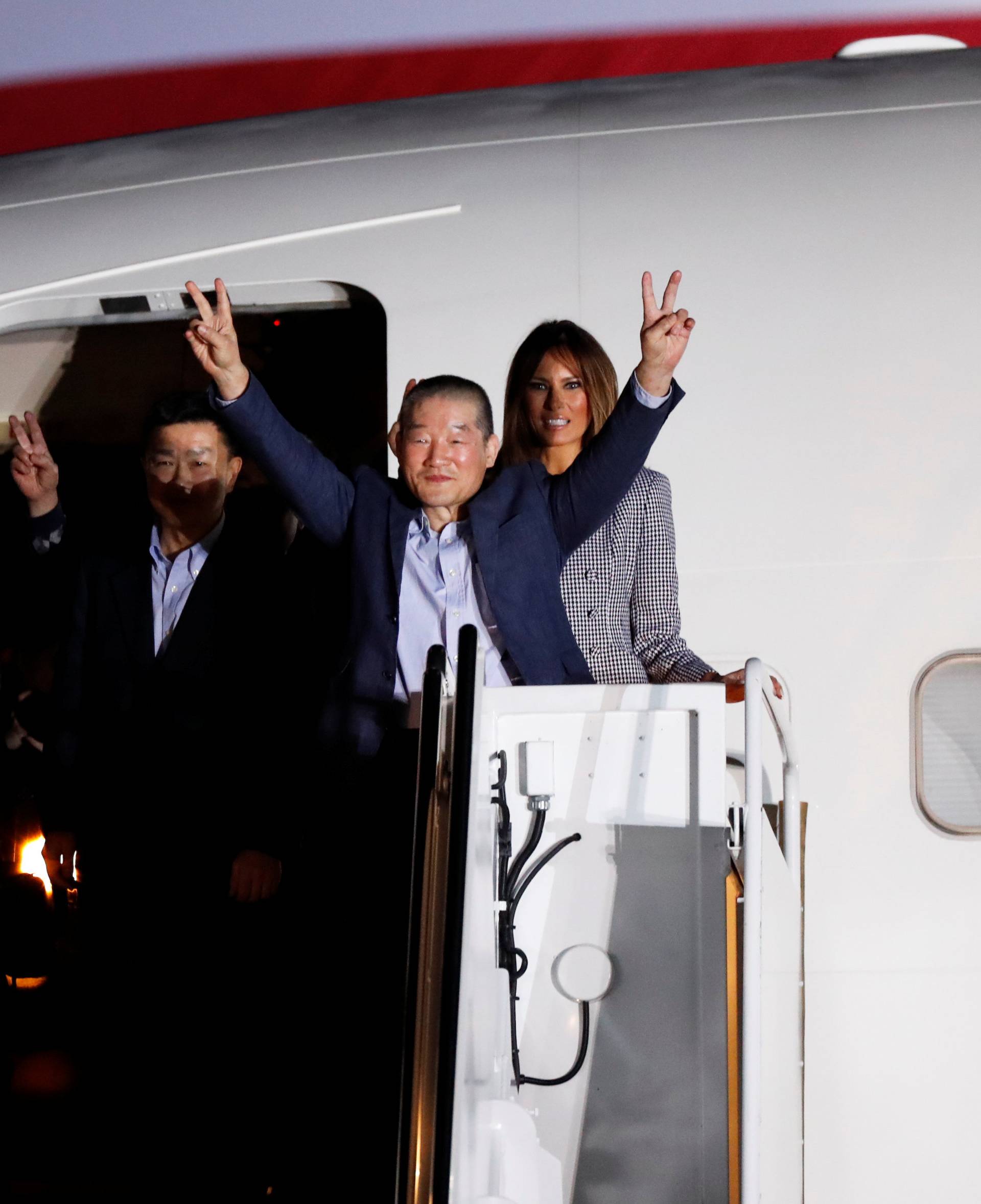 Two of the Americans formerly held hostage in North Korea gesture next to U.S.President Donald Trump and first lady Melania Trump, upon their arrival at Joint Base Andrews