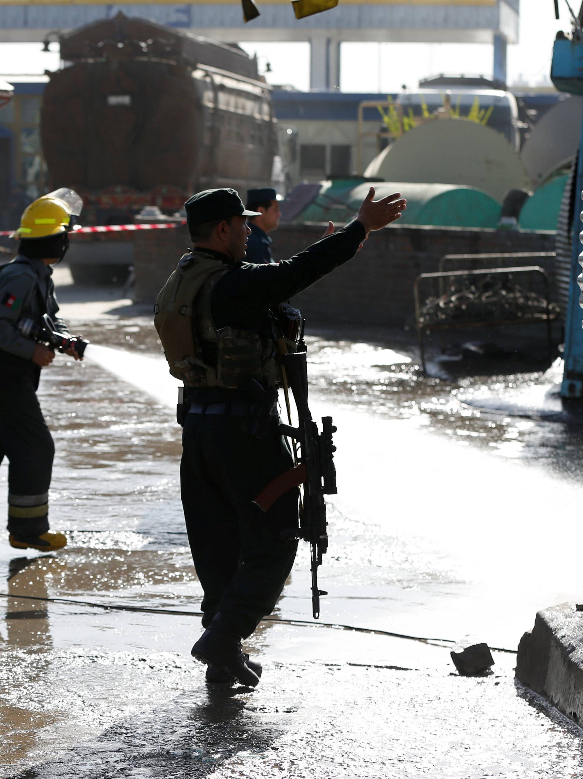 Afghan fire-fighters and members of security forces clean the site of a suicide attack in Kabul