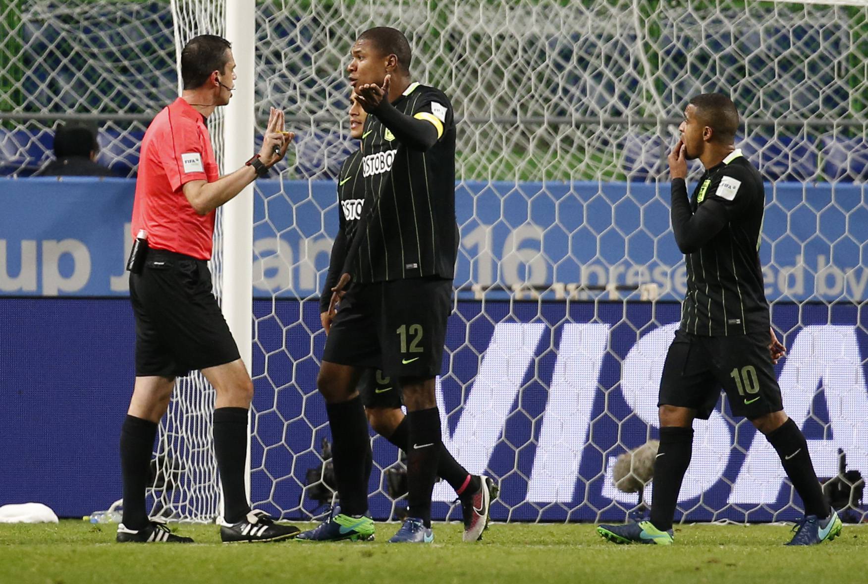 Atletico Nacional's Alexis Henriquez and teammates remonstrate with referee Viktor Kassai after he awarded a penalty to Kashima Antlers