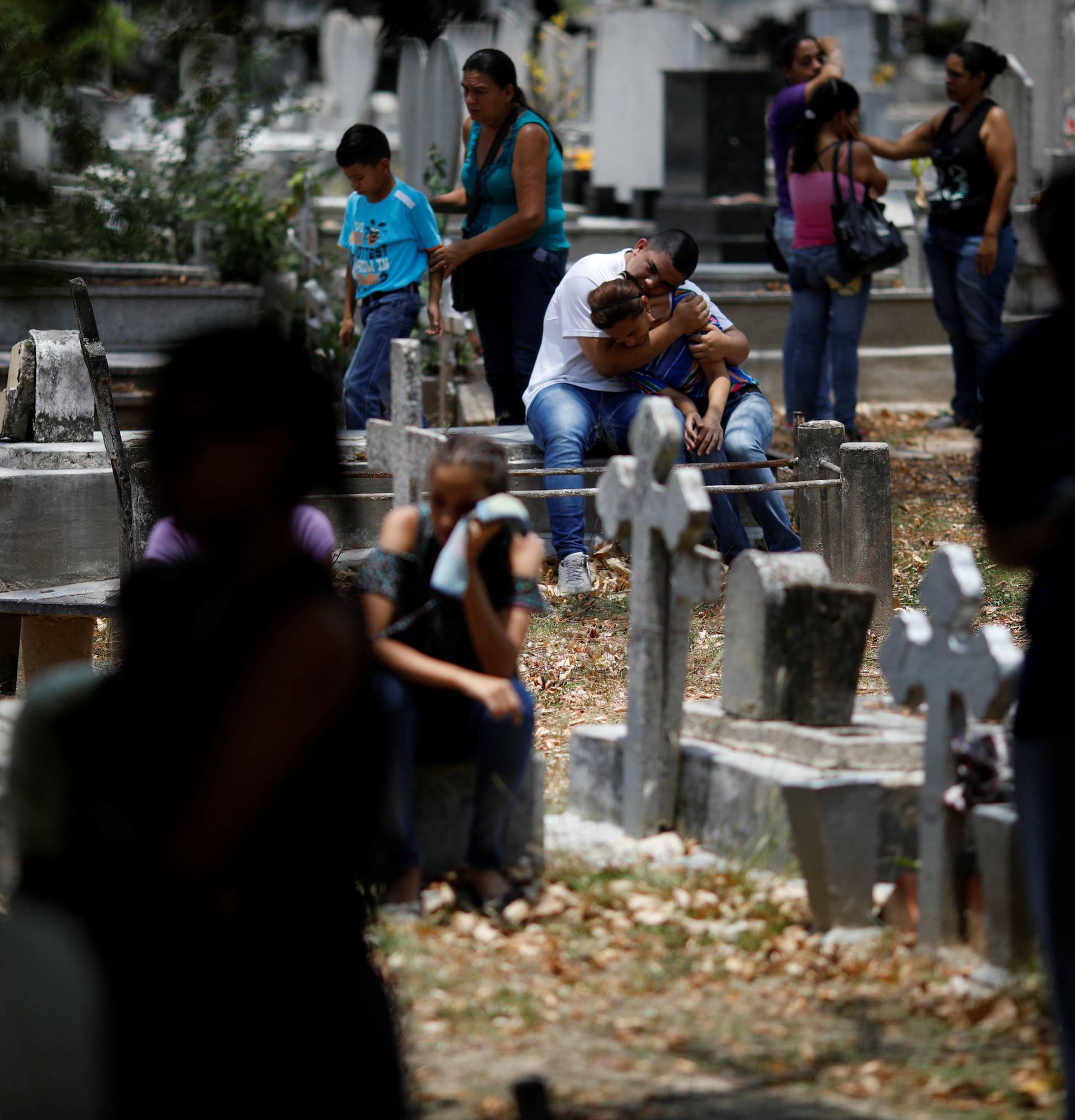 People grieve during the funeral of Javier Rivas, one of the inmates who died during a riot and fire in the cells of the General Command of the Carabobo Police, at the cemetery in Valencia