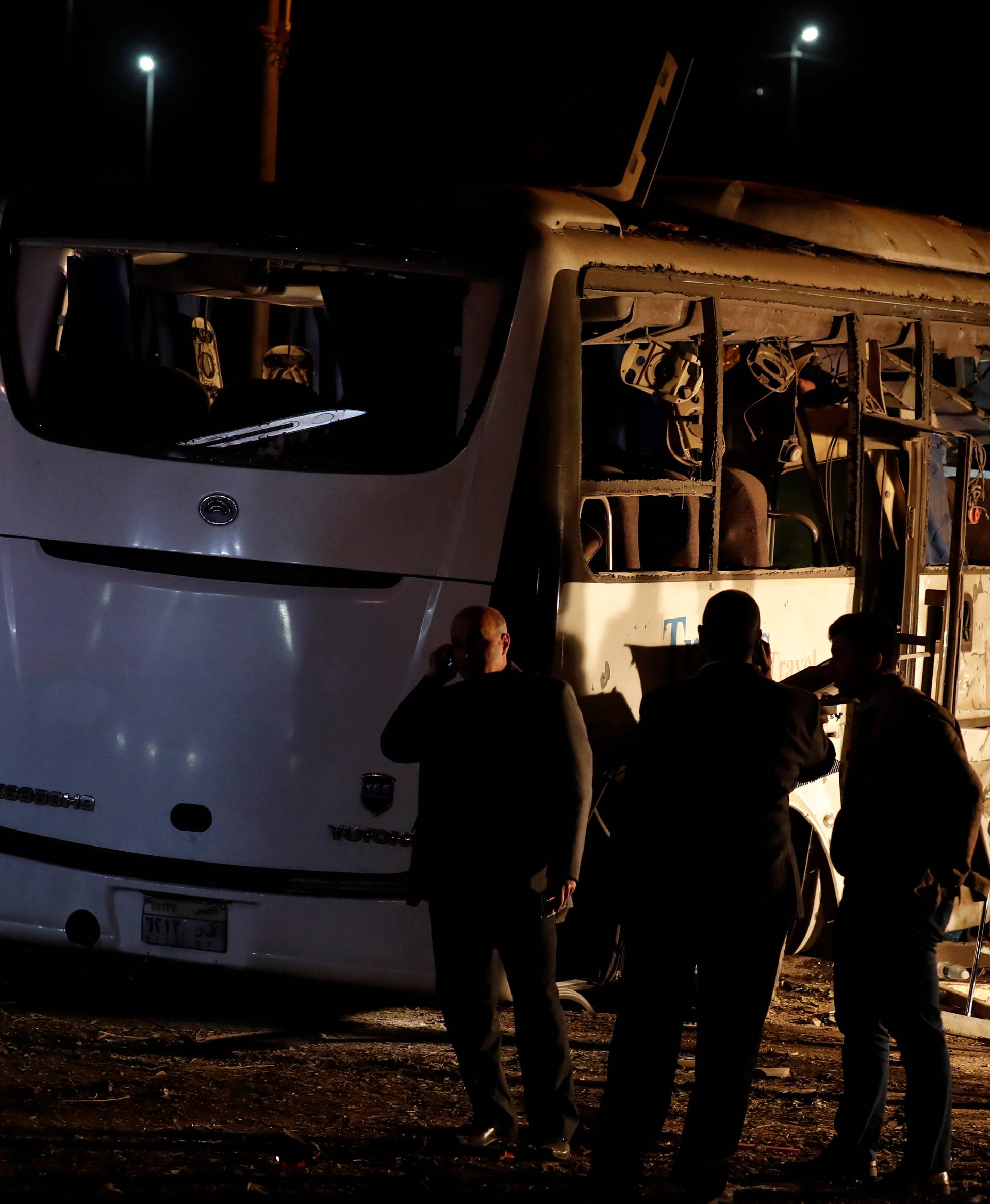 Police officers and officials inspect a scene of a bus blast in Giza