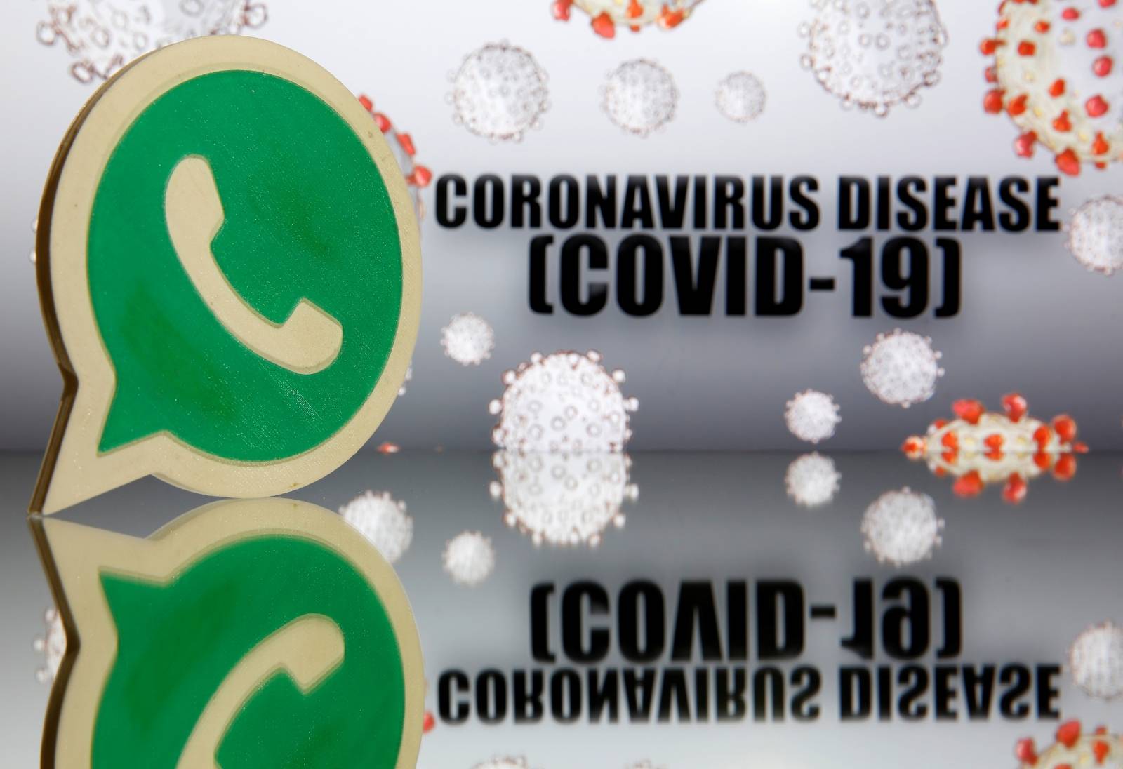 A 3D-printed Whatsapp logo is seen in front of displayed coronavirus disease (COVID-19) sign