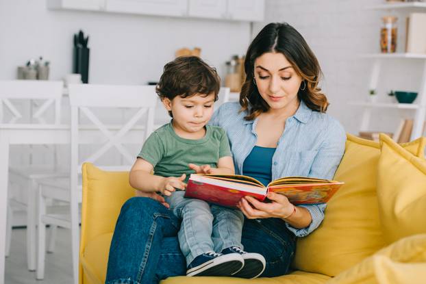 Mom,And,Son,Sitting,On,Yellow,Sofa,And,Reading,Book