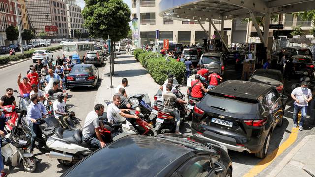 Motorbike and car drivers wait to get fuel at a gas station in Beirut