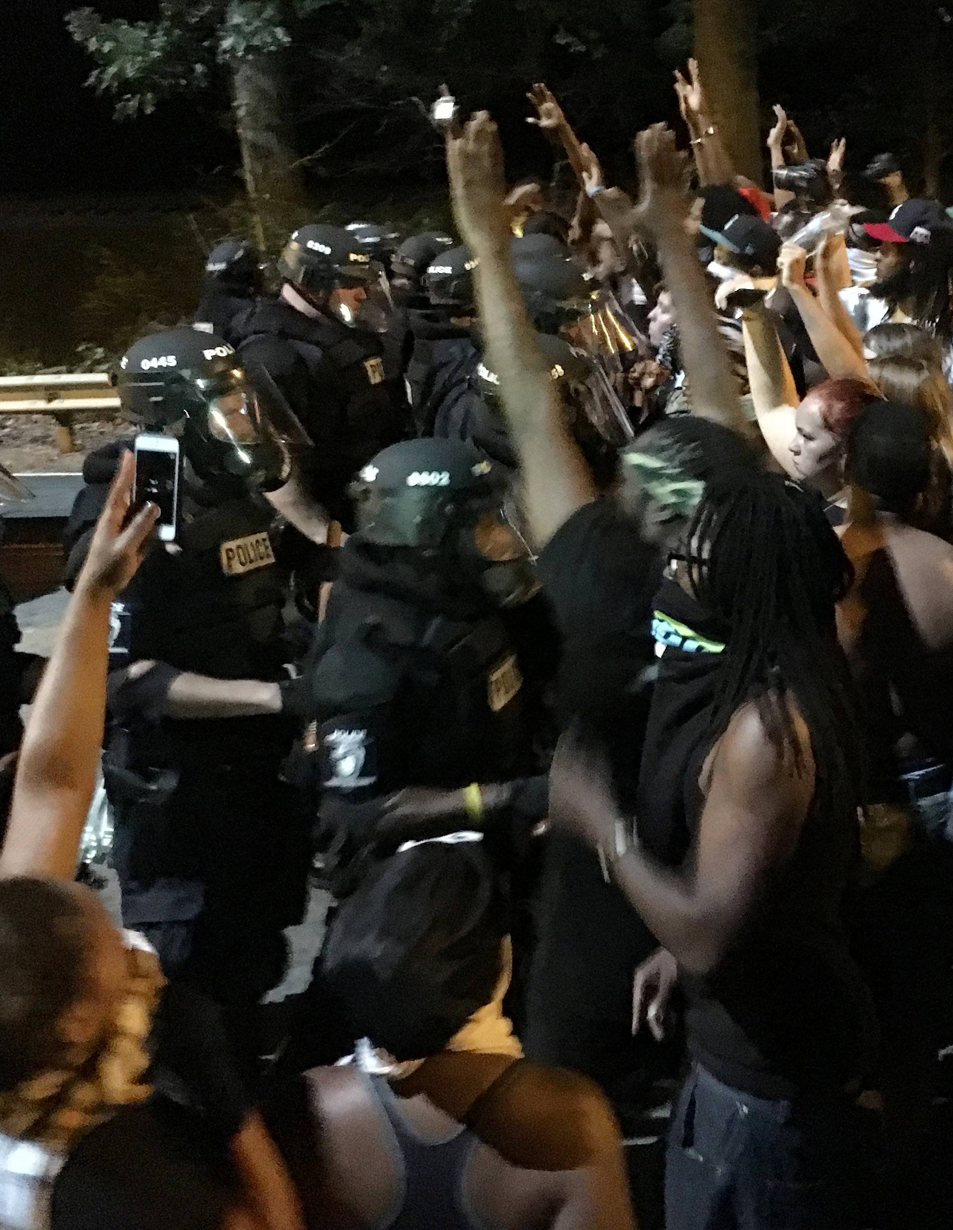 Protestors demonstrate in front of police officers wearing riot gear after police fatally shot Keith Lamont Scott in the parking lot of an apartment complex in Charlotte