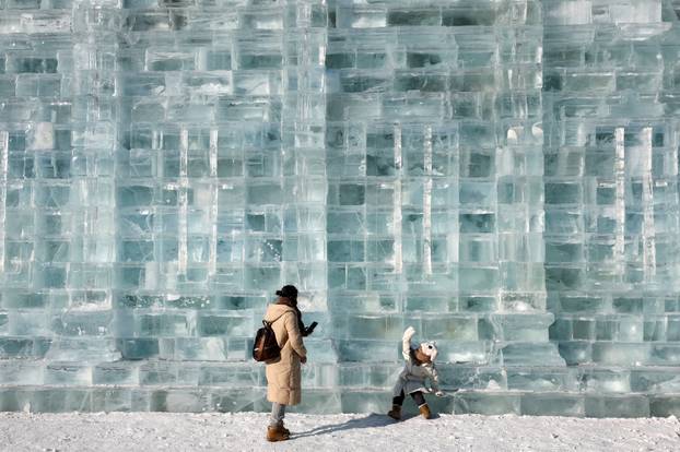 A child poses in front of an ice wall at the annual Ice and Snow Festival in Harbin