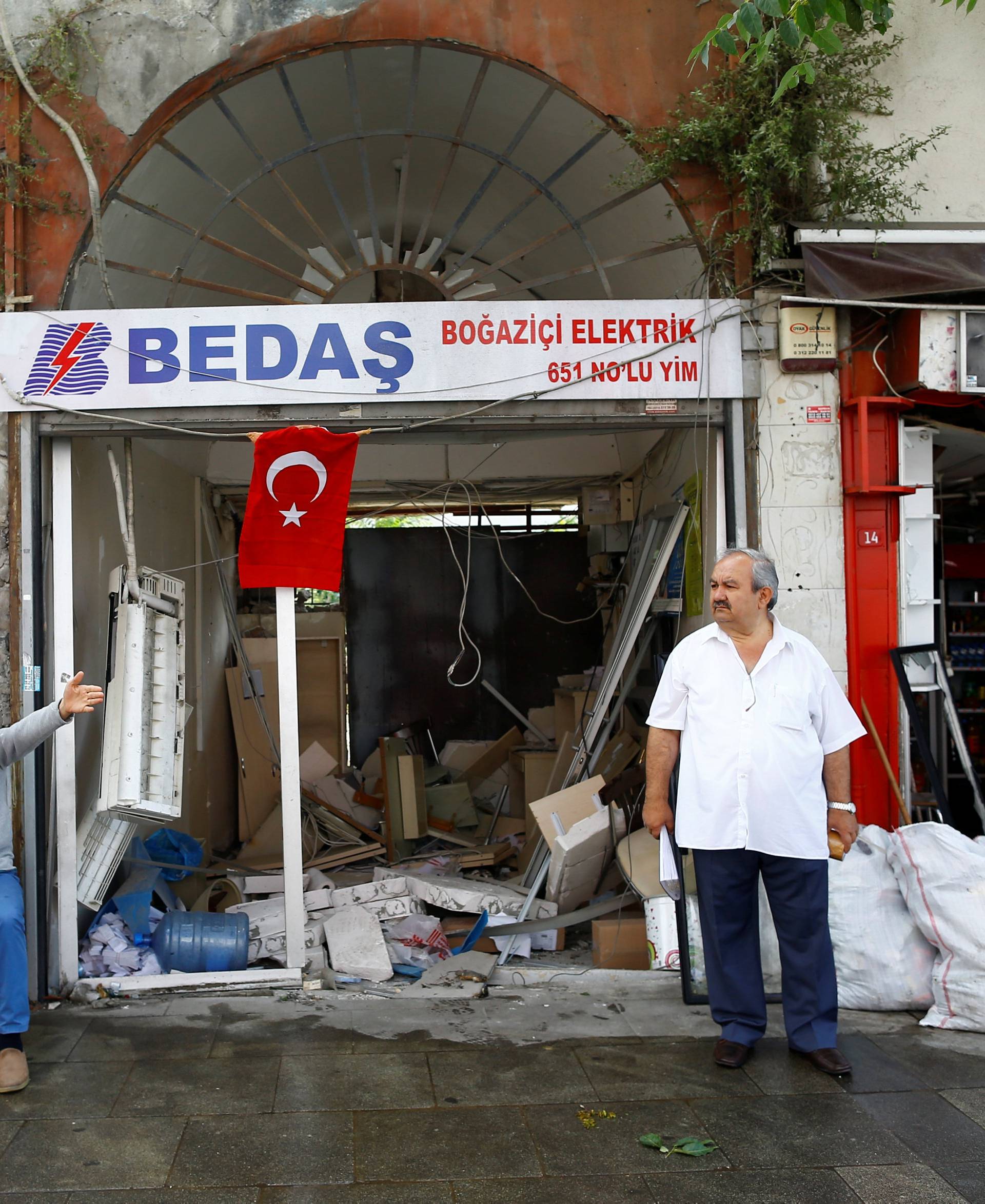 Men sit in front of their damaged shops near the scene of Tuesday's car bomb attack on a police bus, in Istanbul