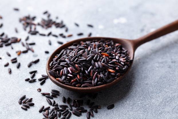 Black,Wild,Rice,In,A,Wooden,Spoon.,Grey,Stone,Background.