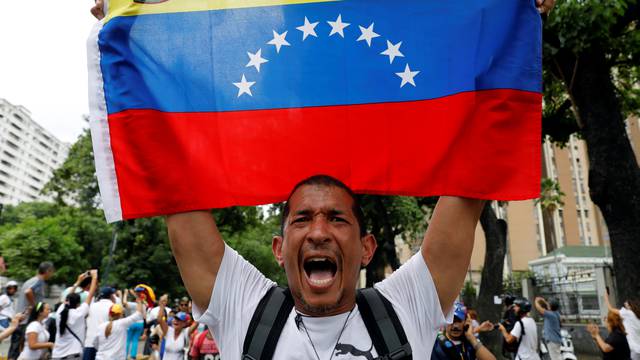 A demonstrator holds a Venezuelan flag as he takes part in a rally to honour victims of violence during a protest against Venezuela's President Nicolas Maduro's government in Caracas