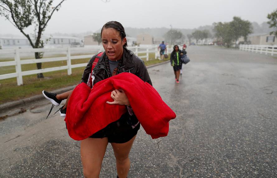 During a driving rain, Maggie Belgie of The Cajun Navy, carries a child evacuating a flooding trailer community during Hurricane Florence in Lumberton