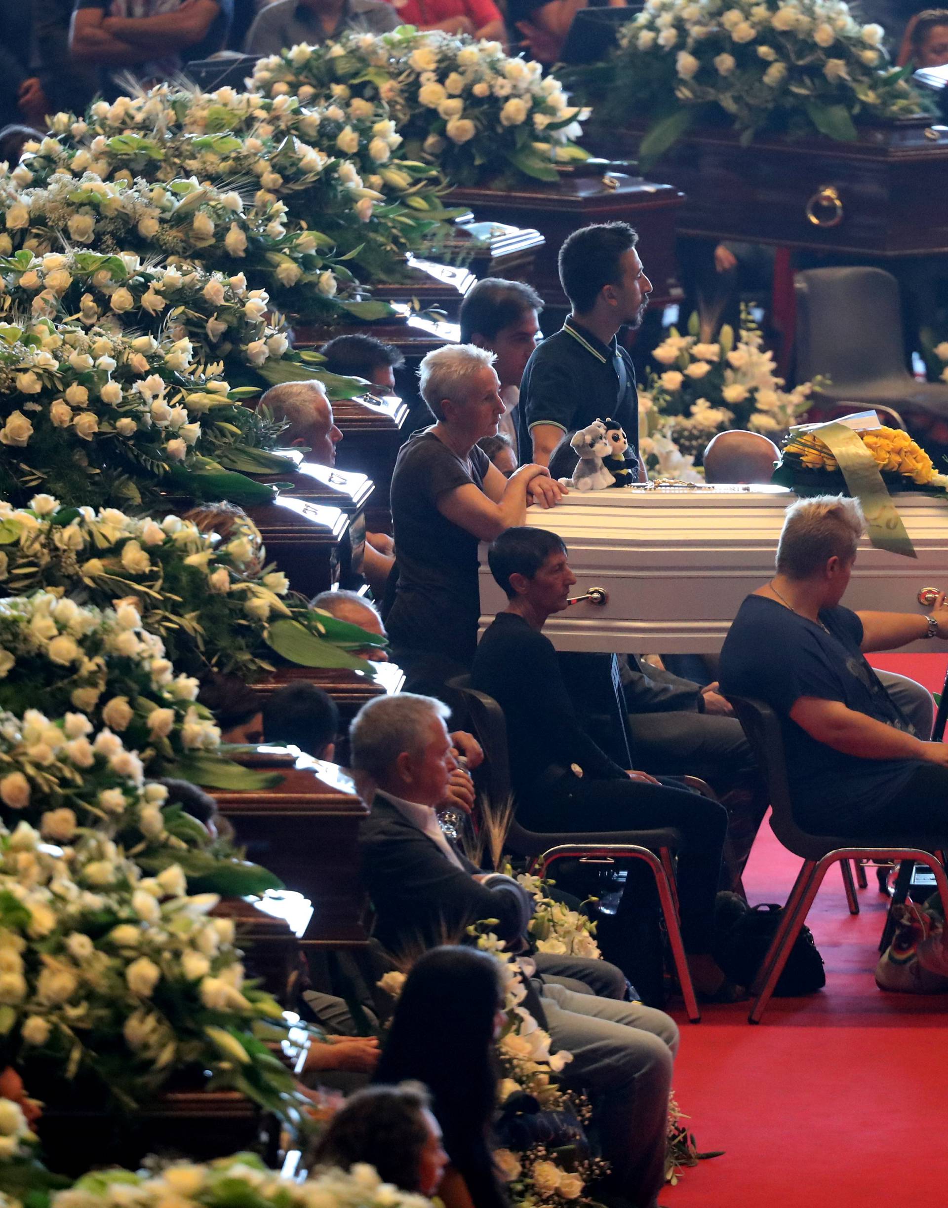 A relative touches the coffin during the state funeral of the victims of the Morandi Bridge collapse, at the Genoa Trade Fair and Exhibition Centre in Genoa