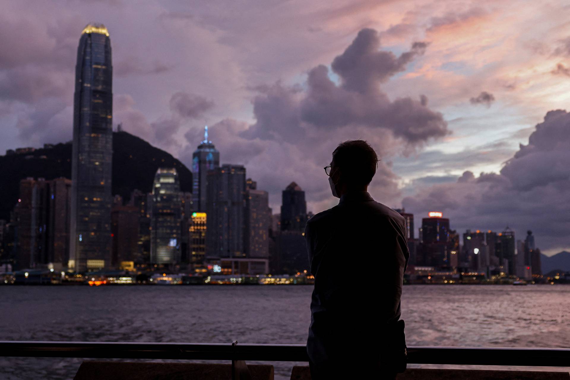 A man stands in front of Victoria Harbour, with the Central financial district in the background, as typhoon Yagi approaches in Hong Kong