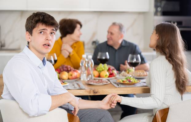 Upset young guy at family holiday table with parents. Unpleasant discussion