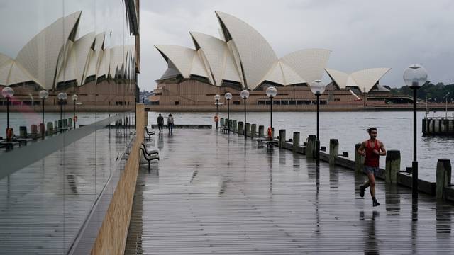 A runner exercises in wet conditions near the Opera House in Sydney