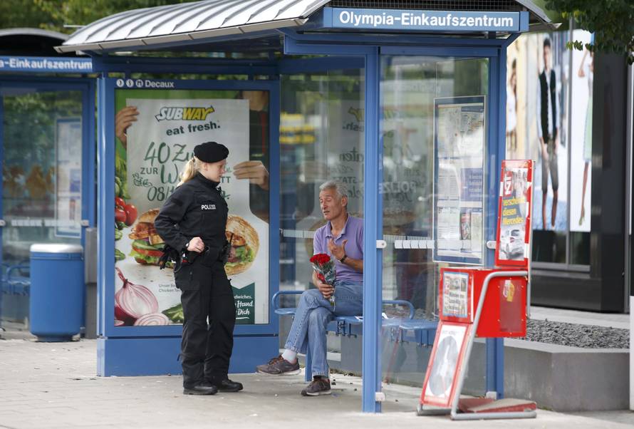 Man holding photo he claims is his slain son speaks to police officer near Olympia shopping mall in Munich
