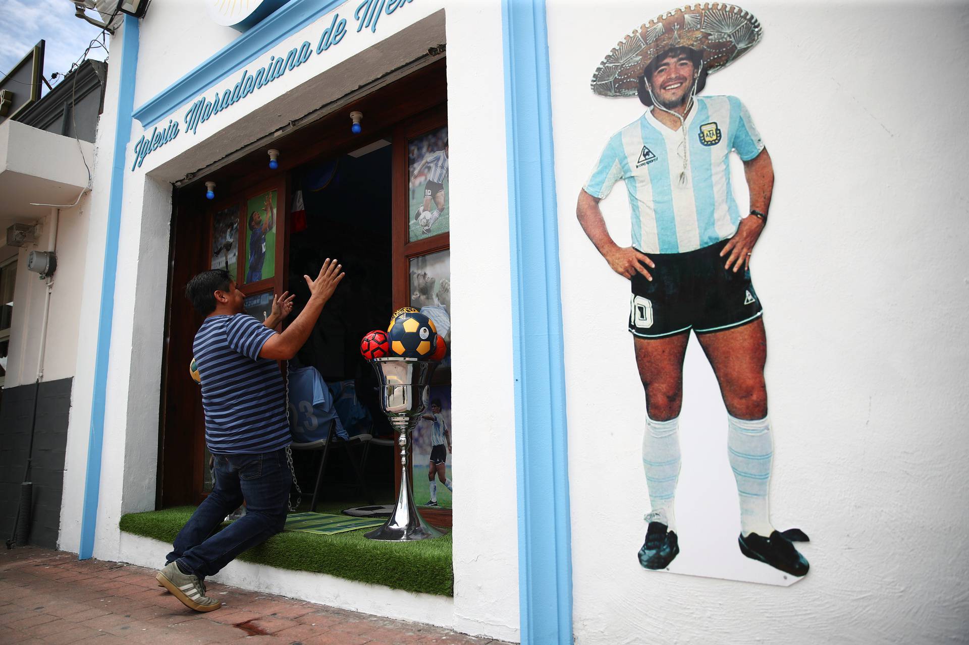A fan kneels at the entrance to the first Mexico's church in memory of soccer legend Diego Armando Maradona in San Andres Cholula