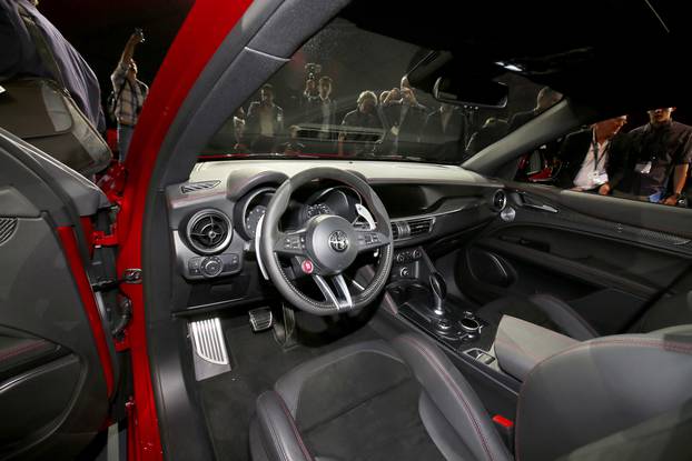 People look over the interior of the car as Alfa Romeo introduces the 2018 Stelvio SUV at the 2016 Los Angeles Auto Show in Los Angeles