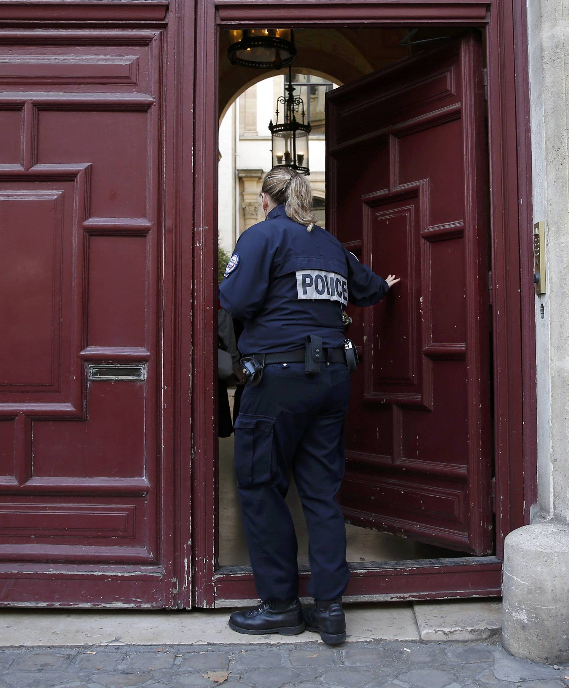 A police officer stands guard at the entrance of a luxury residence on the Rue Tronchet in Paris